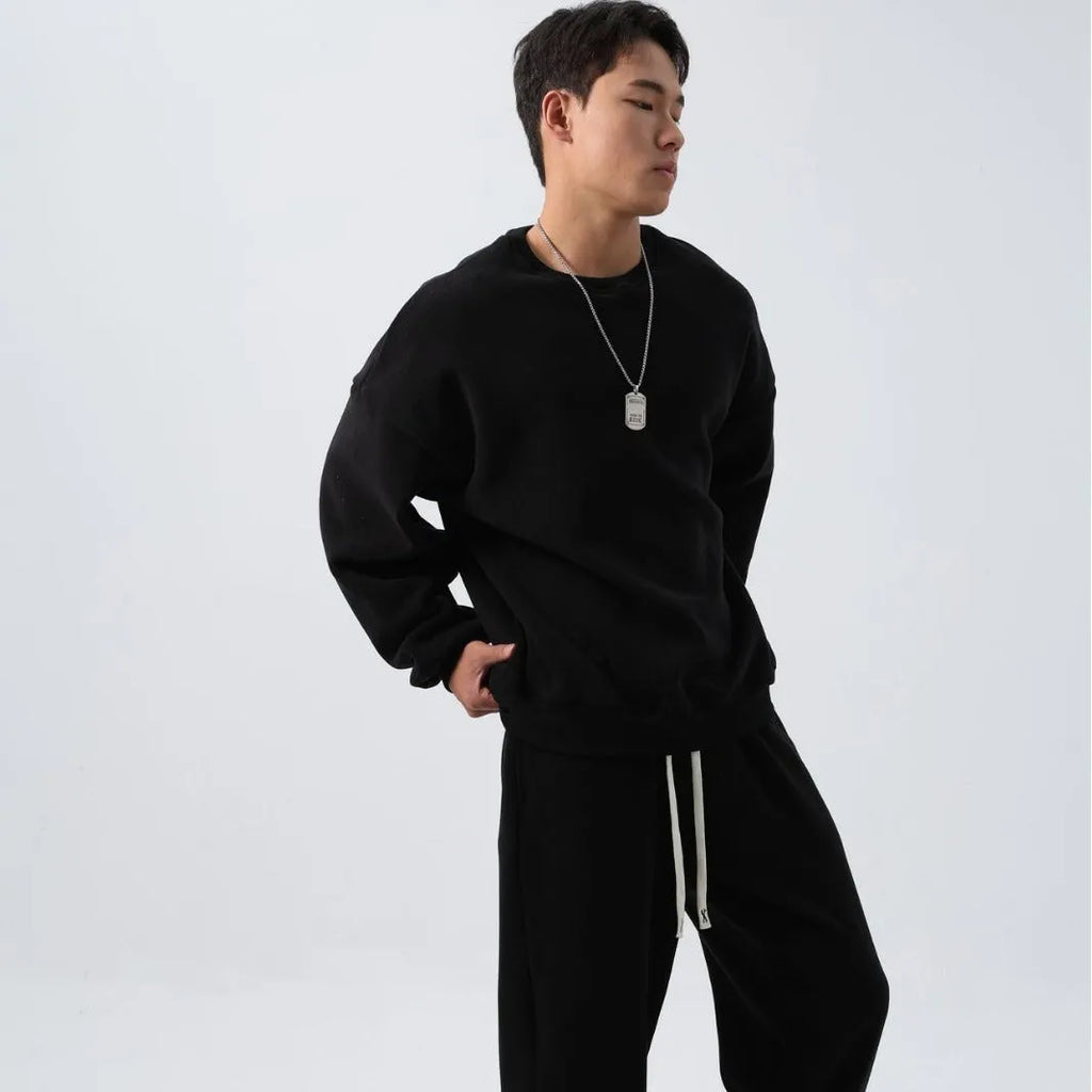 Man wearing a loose black polar fleece sports suit with a crew neck coat and trousers.
