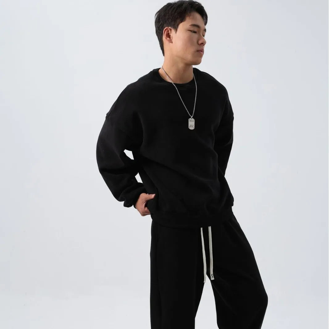 Man wearing a loose black polar fleece sports suit with a crew neck coat and trousers.
