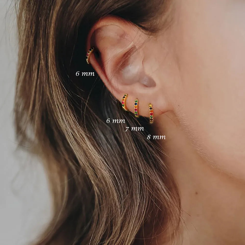 Perforated circle stud earrings with zircon detail in gold, rose gold, and silver colours on a white background.