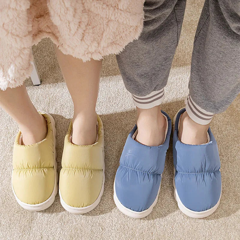 Blue down cotton indoor slippers with thick rubber sole and plush lining, shown on a wooden floor.