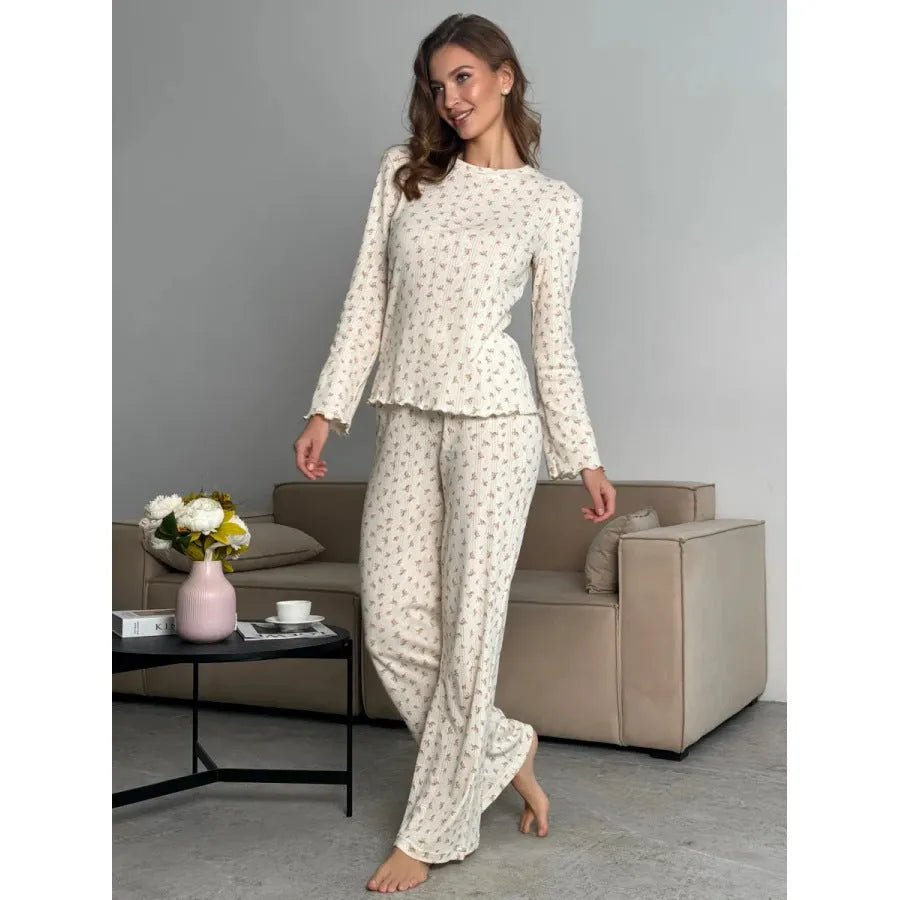 White floral print women's two-piece suit with bell sleeve top and wide leg trousers laid flat.
