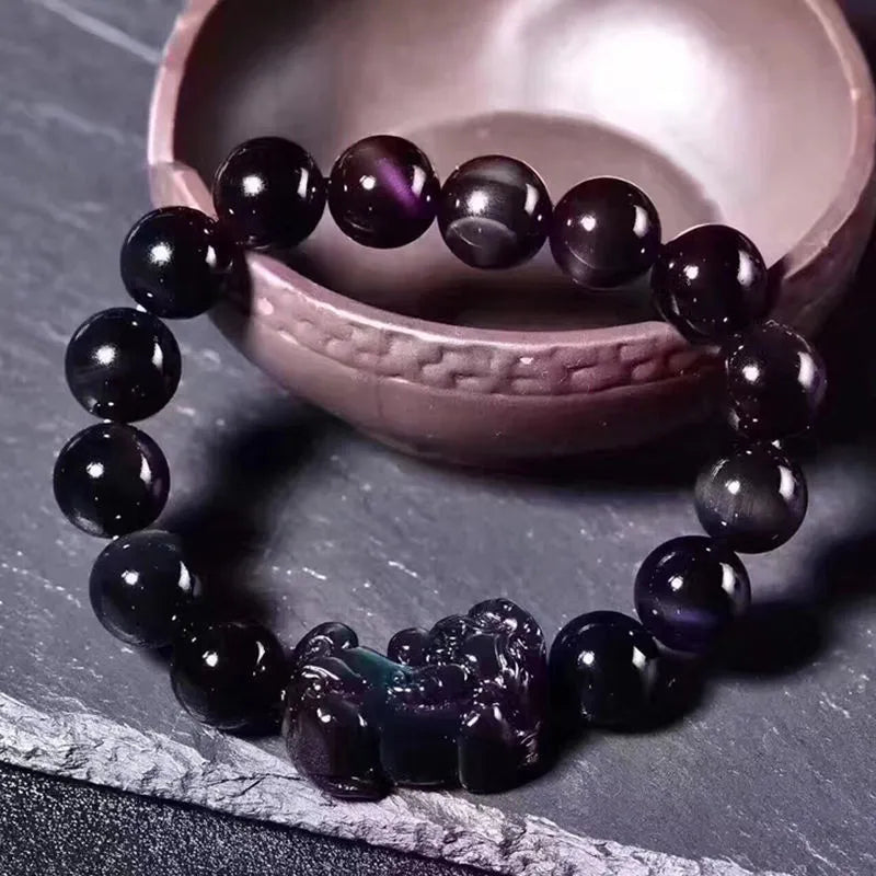 Natural ice colour eye obsidian crystal bracelet on a wrist, showing detail of the stone beads.