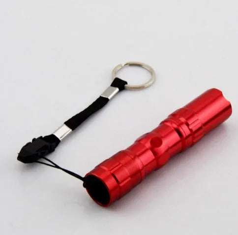 Black aluminium alloy mini LED handheld flashlight next to a AA battery