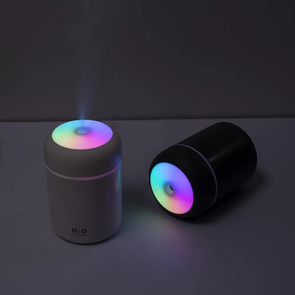 Pink USB desktop humidifier with coloured lights and water tank on a wooden desk