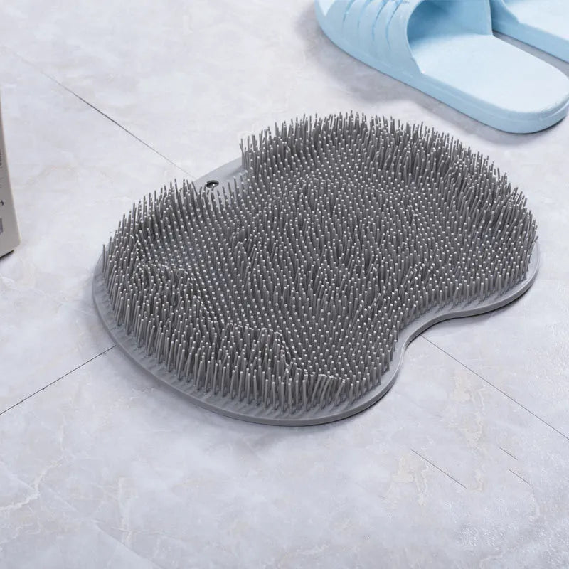 Orange silicone bath massage brush mat with suction cups on a bathroom floor