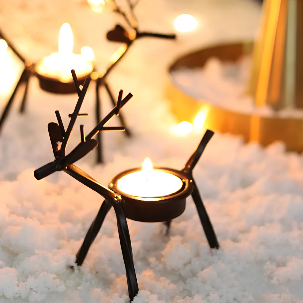 Black iron Christmas candlestick holder with decorative elk design on a table.