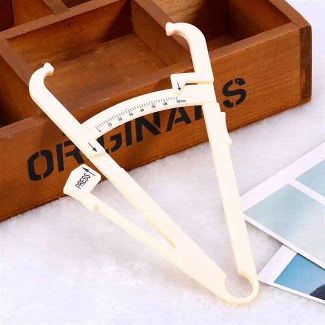 White acrylic body fat caliper with measurement scale for skinfold thickness testing.