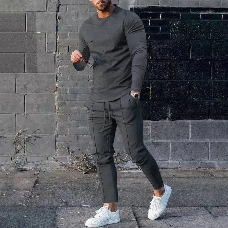 Man wearing a light grey round-neck long-sleeve t-shirt and matching trousers from a two-piece polyester suit set.