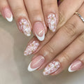 Short almond shaped press-on nails with French style glitter floral designs on a glossy background.
