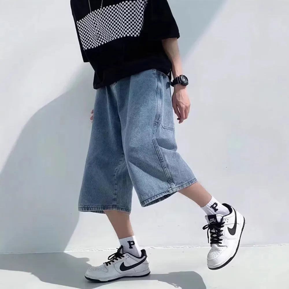 Man wearing blue washed denim high waist pirate shorts with a cropped, straight leg