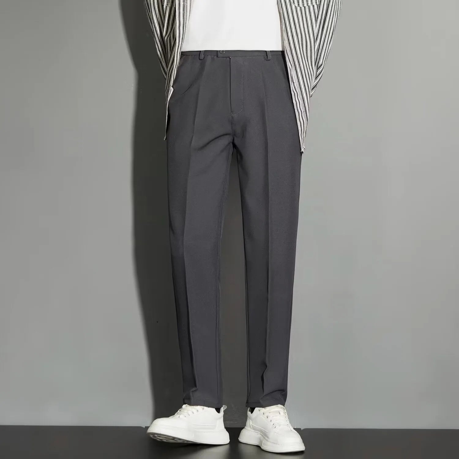 Man wearing straight-leg suit trousers with an ankle-length draping effect in a light colour.
