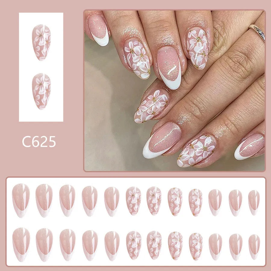 Short almond shaped press-on nails with French style glitter floral designs on a glossy background.