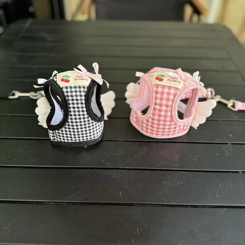 Pink and black small dog harnesses with a hand-holding rope connected at chest and back points.