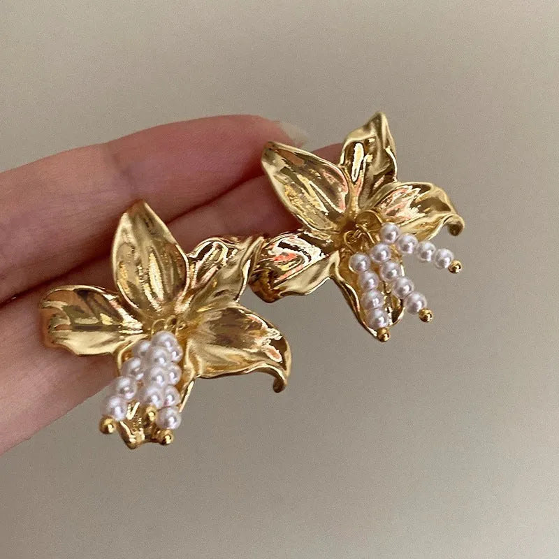 Gold H1795 flower earrings with exaggerated pearl accents on metal construction