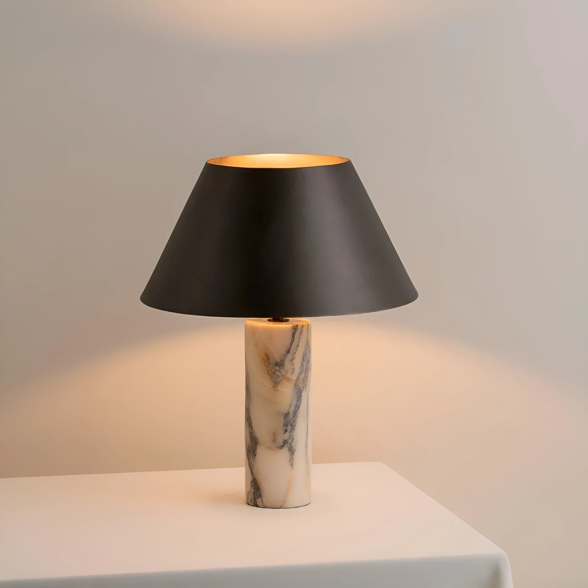 Black modern table lamp with a marble base on a wooden desk.