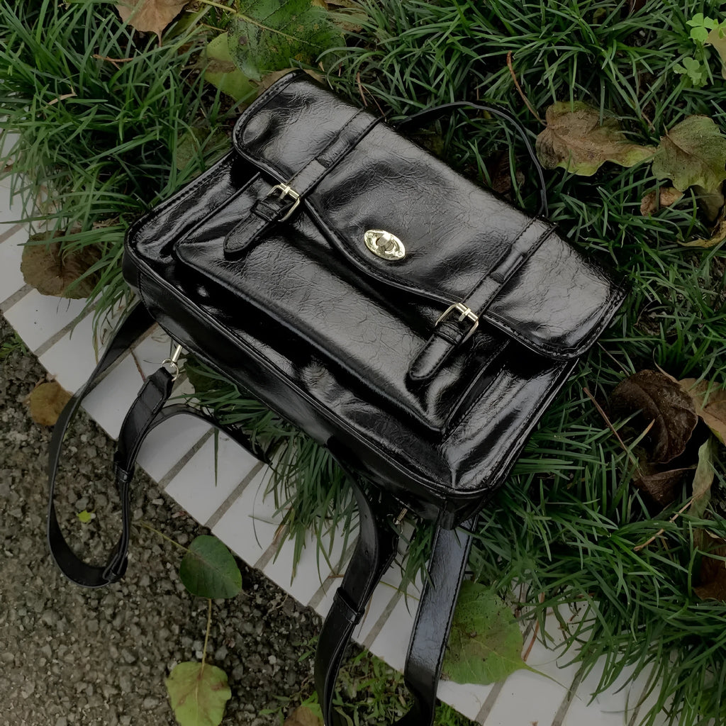 Black college style messenger bag with oil wax leather finish showing organisational compartments and shoulder strap