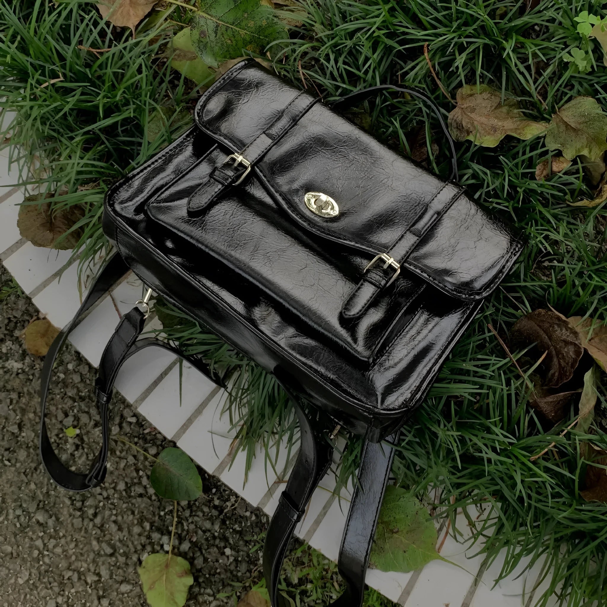 Black college style messenger bag with oil wax leather finish showing organisational compartments and shoulder strap