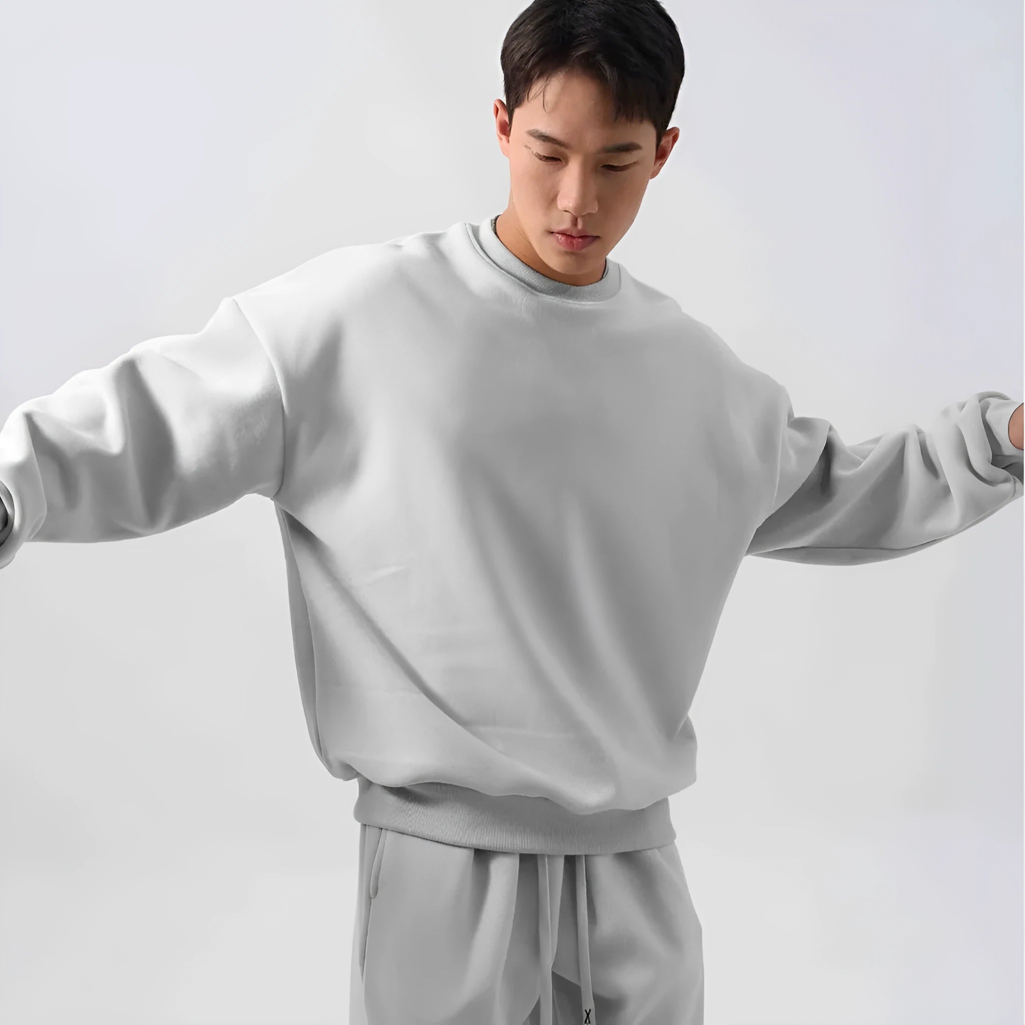 Man wearing a loose black polar fleece sports suit with a crew neck coat and trousers.