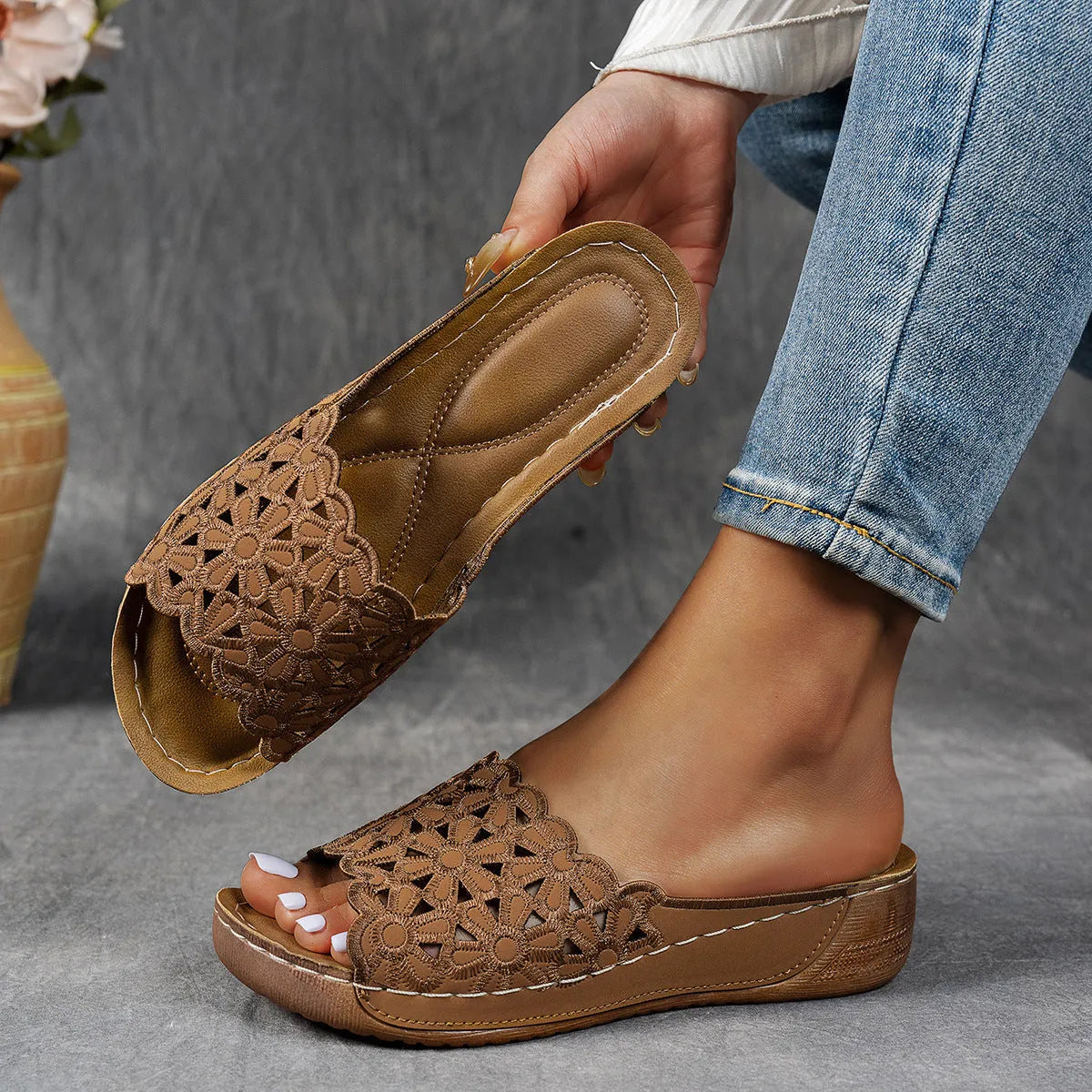 Women's black beach slipper with flower cutouts, a fish mouth toe, and a low wedge heel on a rubber sole.