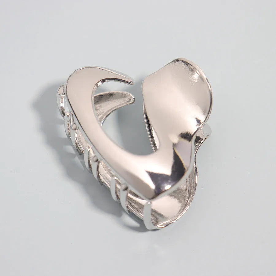 Assortment of silver metal hair claw barrettes with various designs including bows, pearls, and geometric shapes.