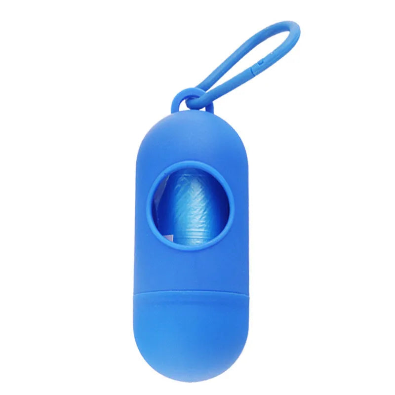 Compact black dog poop bag holder with Velcro strap and metal side hook, shown next to a roll of waste bags.