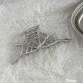 Assortment of silver metal hair claw barrettes with various designs including bows, pearls, and geometric shapes.