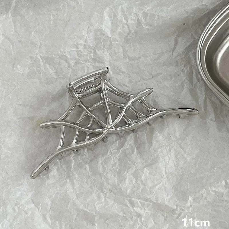 Assortment of silver metal hair claw barrettes with various designs including bows, pearls, and geometric shapes.