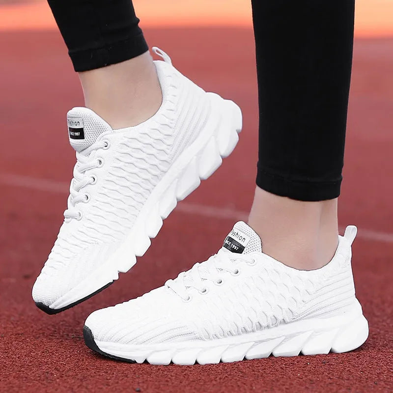 Women's running shoes in black, pink and white colours showing fly weave upper and durable outsole