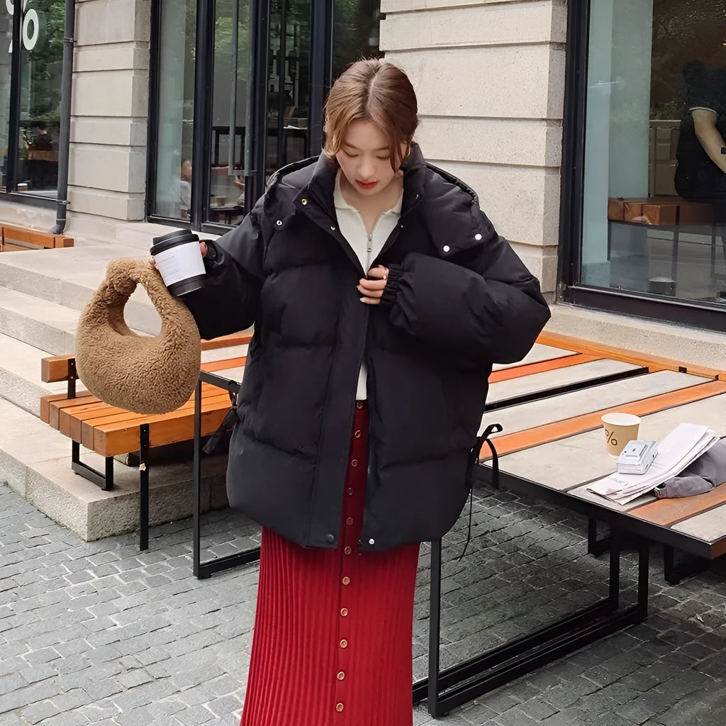 Women's loose black padded winter jacket with princess sleeves on a hanger.