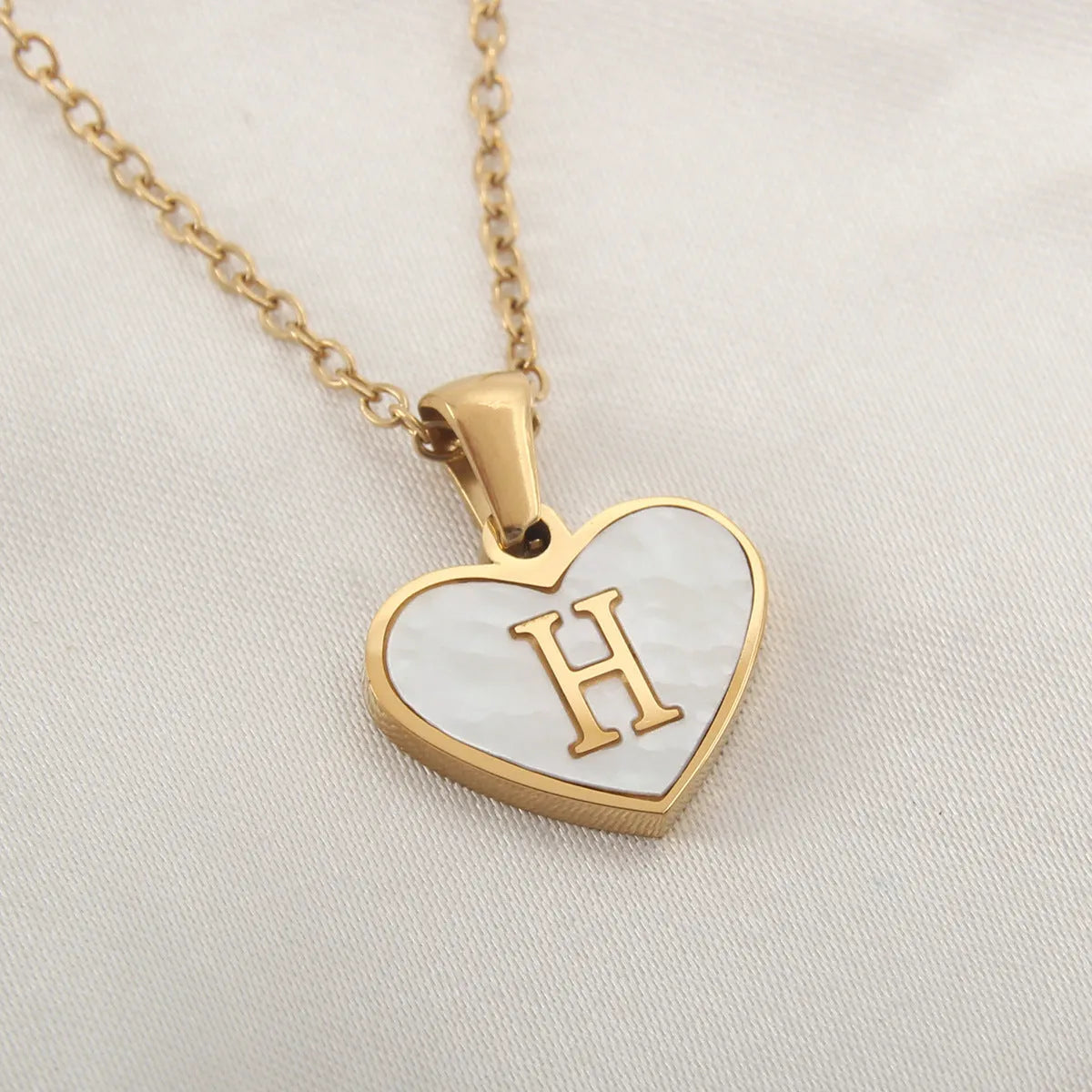 Gold plated heart-shaped white shell pendant personalised initial necklace on a stainless steel chain.