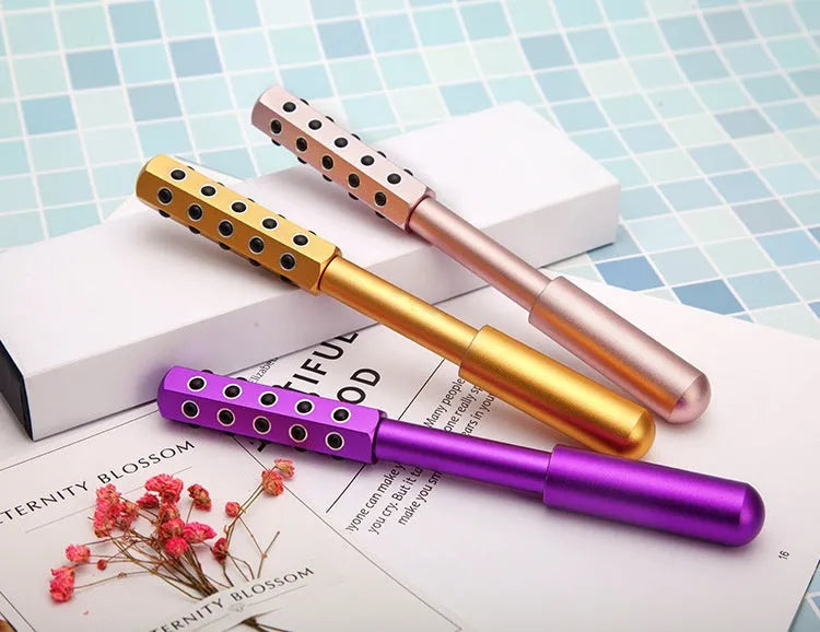 Purple stainless steel facial massage roller with germanium particle ball head on a white background.