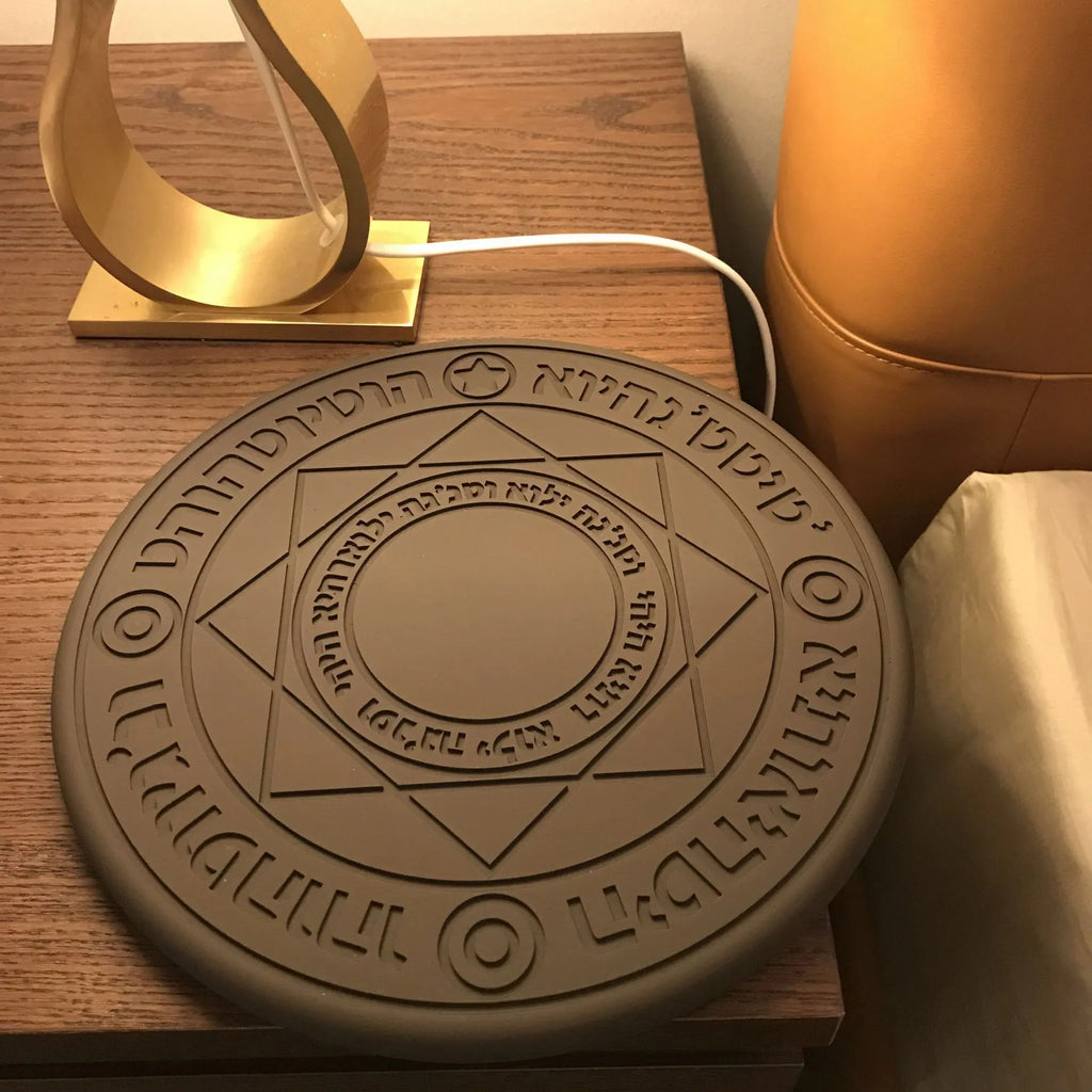 Black 10W fast wireless phone charger with glowing magic array pattern on a desk.