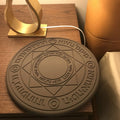 Black 10W fast wireless phone charger with glowing magic array pattern on a desk.