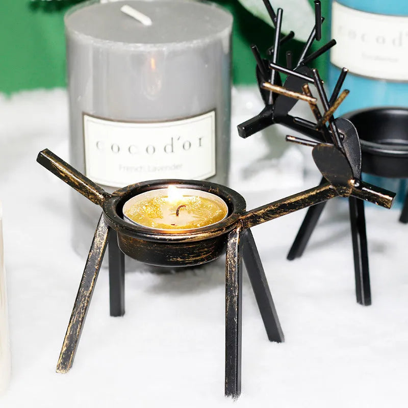 Black iron Christmas candlestick holder with decorative elk design on a table.