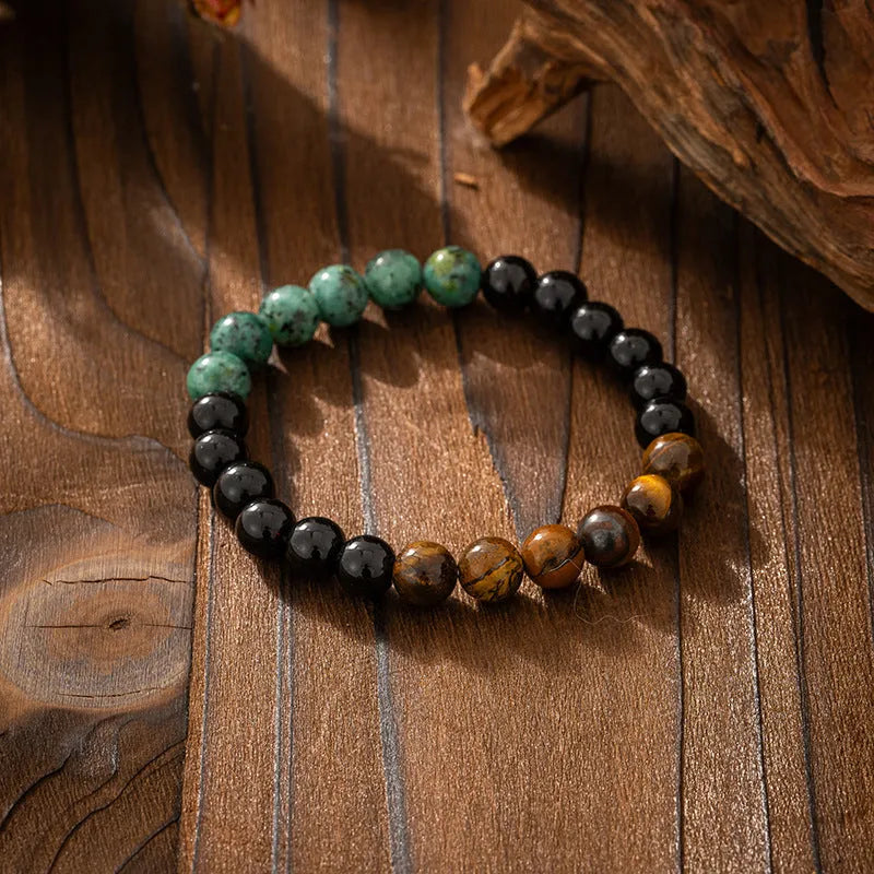 Long natural stone beaded sweater chain necklace and matching bracelet in bohemian style on a grey background.