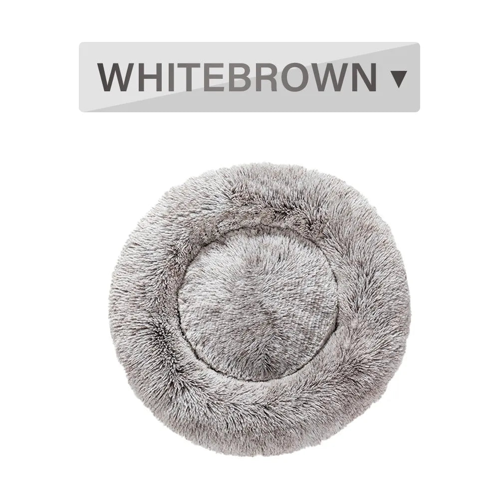 Fluffy donut-shaped dog bed in long plush fabric, shown in a light grey colour with a raised edge.