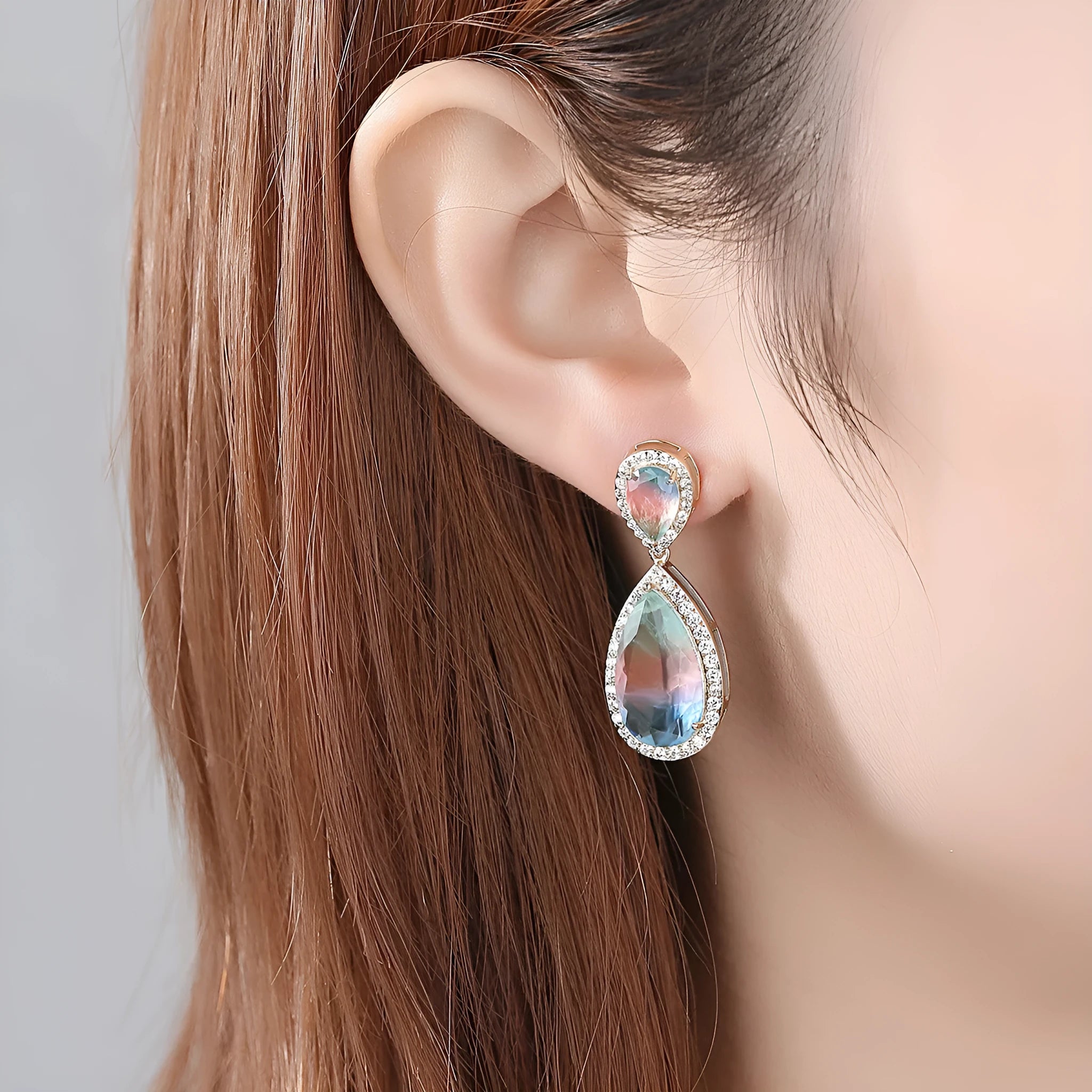 Drop shape copper earrings with inlaid synthetic gemstone in blue colour option on a white background