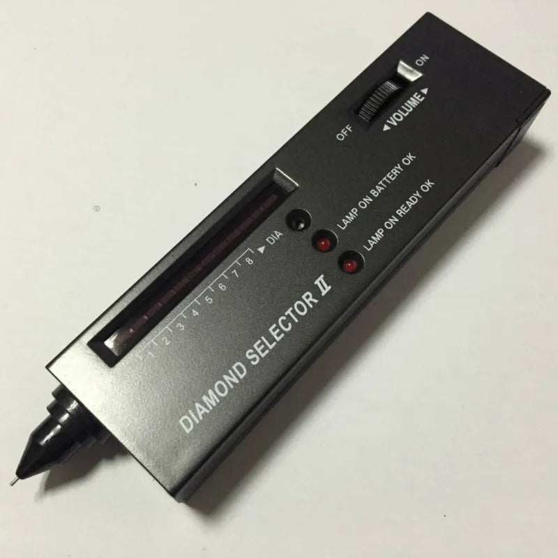 Handheld black diamond thermal conductivity tester with metal probe on a gemstone.