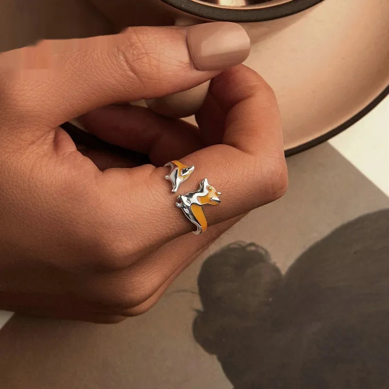 Silver corgi pet cartoon ring with electroplated colour on a model's finger.