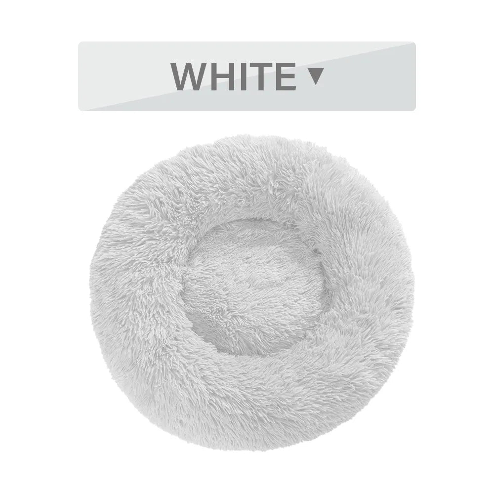 Fluffy donut-shaped dog bed in long plush fabric, shown in a light grey colour with a raised edge.