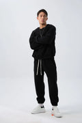 Man wearing a loose black polar fleece sports suit with a crew neck coat and trousers.