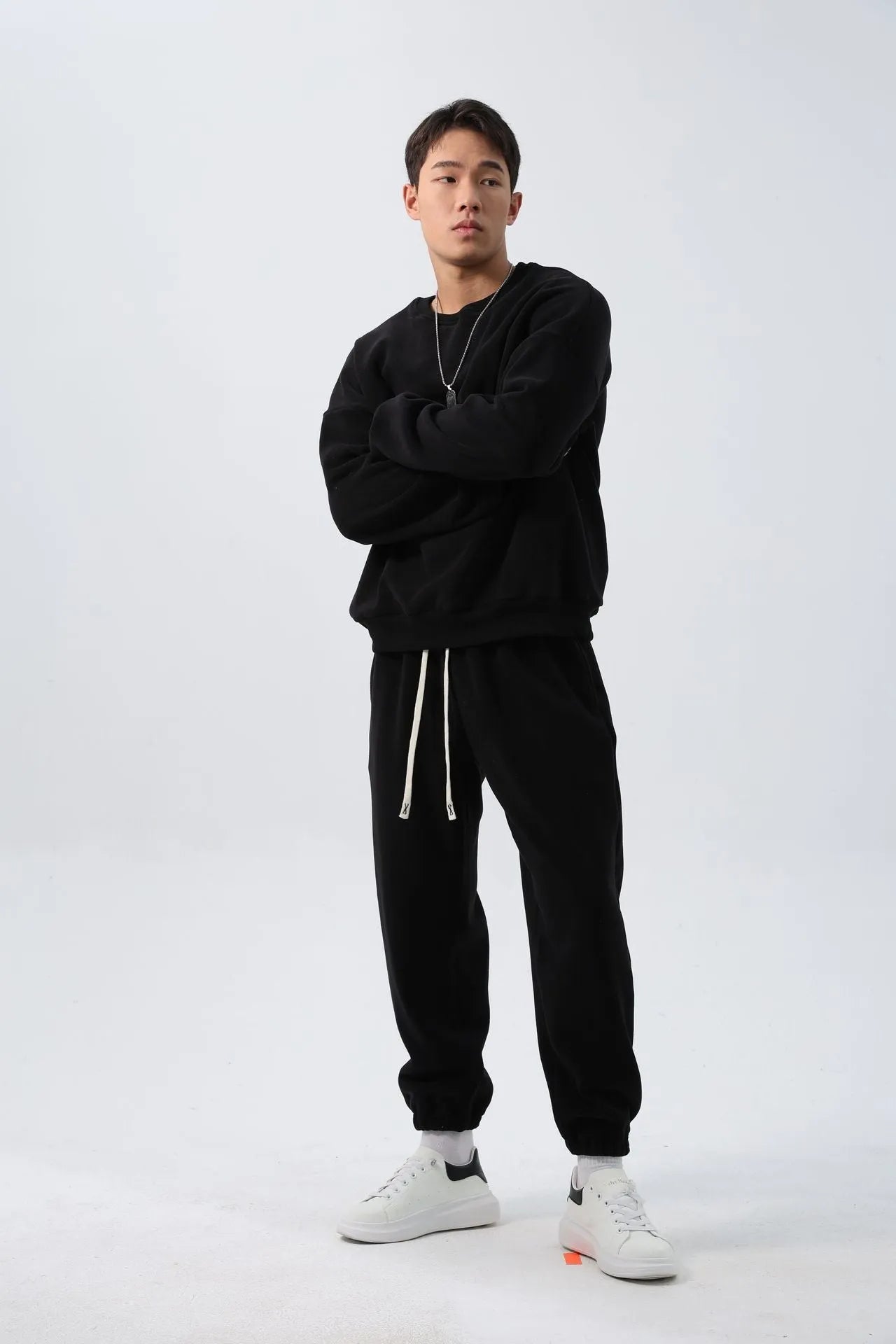 Man wearing a loose black polar fleece sports suit with a crew neck coat and trousers.