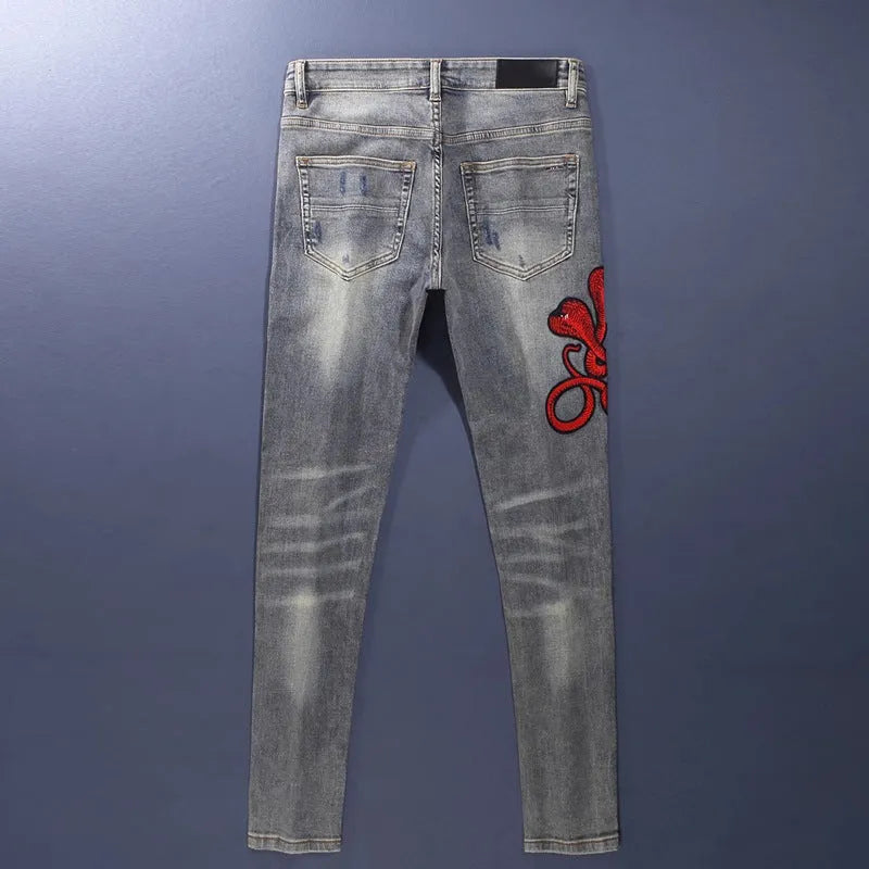 Slim fit jeans with washed-out old colour, distressed holes, and embroidered patches on cotton fabric