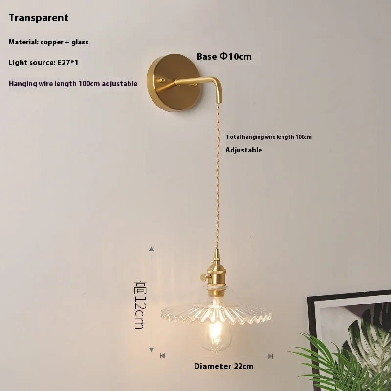 Brass lotus-shaped wall lamp with glass shade in choice of six colours on a plain wall.