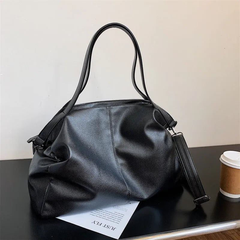 Large soft PU leather messenger bag with adjustable strap in black, shown open with internal pockets.