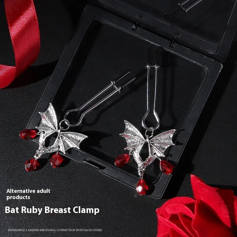 Silver bat-shaped adjustable nipple clamps with ruby decoration on a black background