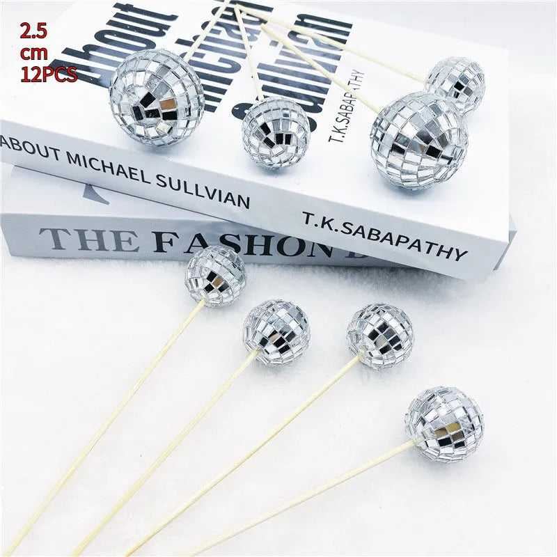 Glass mirror ball cake decoration on a wooden stick, showing reflective surface.