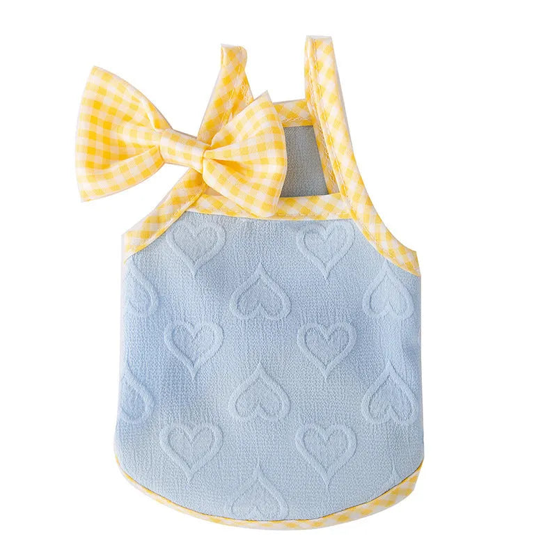 Small dog wearing a blue vest with suspenders and a heart-shaped bow, showing elastic sides.