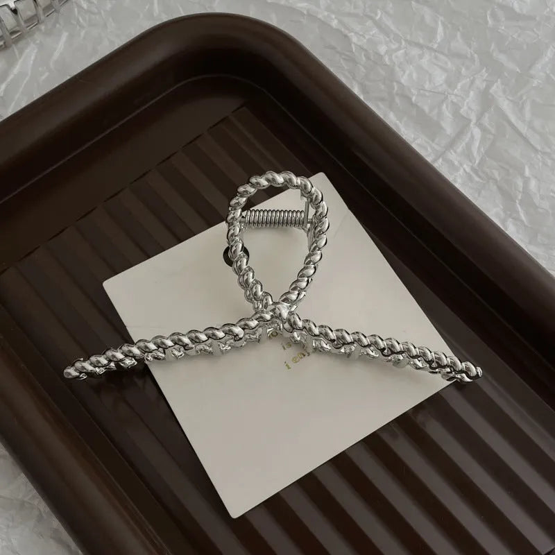 Assortment of silver metal hair claw barrettes with various designs including bows, pearls, and geometric shapes.