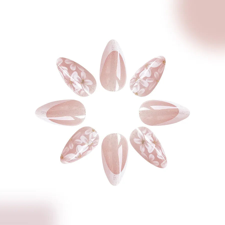 Short almond shaped press-on nails with French style glitter floral designs on a glossy background.